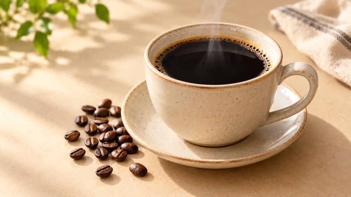 Cup of plain black coffee with coffee beans on a neutral background.