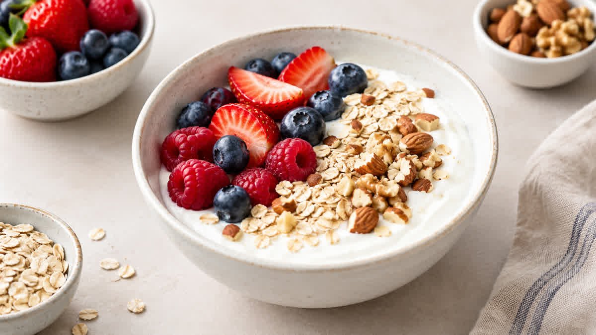 Bowl of plain Greek yogurt topped with fresh berries, oats, and nuts.