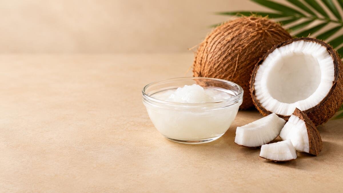 Bowl of coconut oil beside fresh coconut pieces illustrating coconut oil nutrition and potential health effects