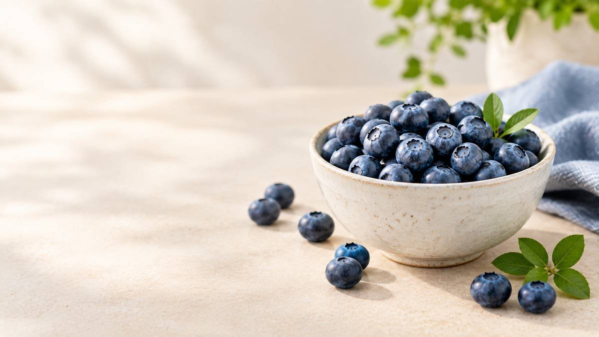 Fresh blueberries in a ceramic bowl on a neutral tabletop.