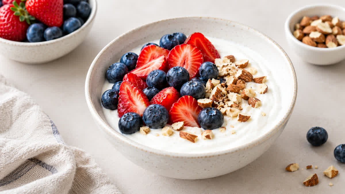 Bowl of plain Greek yogurt topped with fresh blueberries and strawberries.