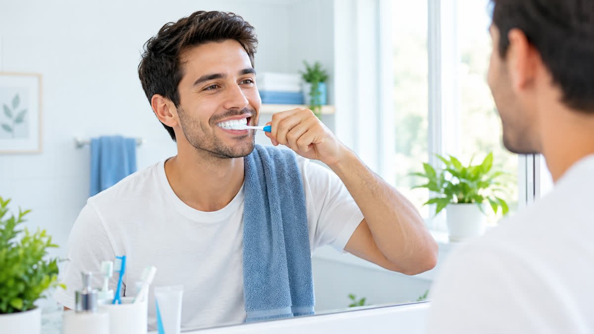 Person brushing teeth as part of a daily routine to help reduce bad breath.