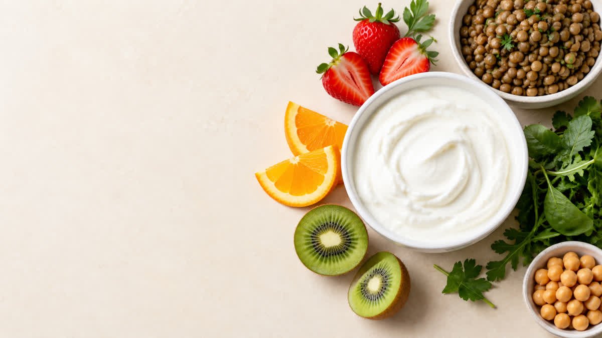 Bowl of plain Greek yogurt with strawberries, orange slices, lentils, and leafy greens