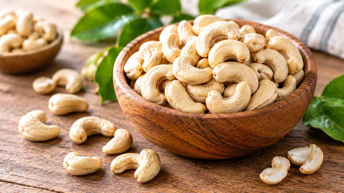 Whole cashew nuts and shelled cashew kernels arranged in a wooden bowl, illustrating the nutritional benefits of cashews.