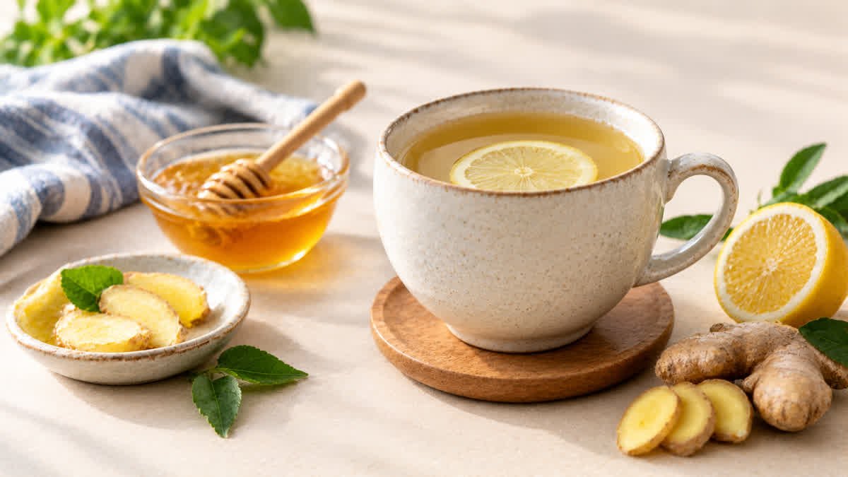 A warm cup of herbal tea on a neutral tabletop with fresh ginger and lemon