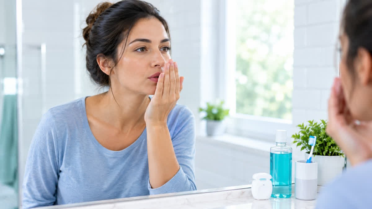 Person checking breath in mirror — 7 common causes of bad breath and how to fix them.